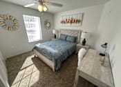 Thumbnail 34 of 48 - A bedroom with a bed, desk, and a ceiling fan.