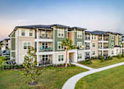 Thumbnail 3 of 46 - Apartment complex with a tree in front.