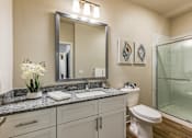Thumbnail 10 of 46 - A bathroom with a toilet, sink, mirror, and a vase of flowers.