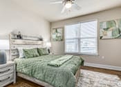 Thumbnail 14 of 46 - A bedroom with a bed, nightstand, and a ceiling fan.