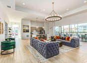 Thumbnail 19 of 46 - A modern living room with a green sofa and a grey tufted ottoman.
