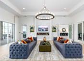 Thumbnail 17 of 46 - A living room with a large blue couch and a chandelier hanging from the ceiling.