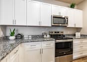 Thumbnail 11 of 46 - A kitchen with white cabinets and a granite countertop.