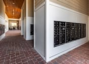 Thumbnail 37 of 46 - A long hallway with a brick floor and a wall of mailboxes.