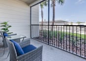 Thumbnail 16 of 46 - A balcony with a chair and a table with a blue cushion.