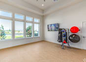 Thumbnail 27 of 46 - A room with a large window, a TV, and exercise equipment.