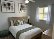 Thumbnail 4 of 29 - A bedroom with a bed, nightstand, and two framed artworks on the wall.