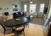 Thumbnail 10 of 29 - A black table with four chairs around it in a room with a blue couch and a painting on the wall.