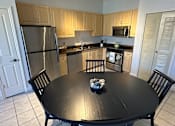 Thumbnail 11 of 29 - A kitchen with a table in the middle and chairs around it.