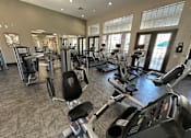 Thumbnail 19 of 29 - A gym with treadmills and elliptical machines.