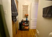Thumbnail 6 of 25 - A hallway with a coat rack and a small table with flowers on it.