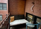Thumbnail 8 of 25 - A small balcony with a bench and a table.