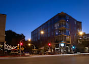 Thumbnail 24 of 31 - A modern building with a glass facade is illuminated by street lights at night.