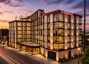 Thumbnail 18 of 18 - A modern building with a red and white facade is illuminated at dusk.
