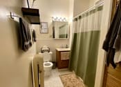 Thumbnail 7 of 25 - A bathroom with a toilet, sink, and a mirror.