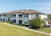 Thumbnail 2 of 21 - A large white building with a brown roof and a green lawn in front.