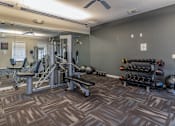 Thumbnail 16 of 24 - A gym with a variety of equipment and weights.