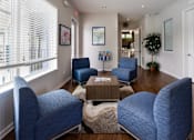 Thumbnail 17 of 21 - A living room with blue chairs and a coffee table.