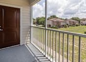 Thumbnail 13 of 21 - A brown door is on the left of a balcony with a metal railing.