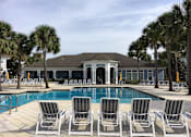 Thumbnail 22 of 44 - A pool with chairs and a building in the background.
