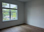 Thumbnail 11 of 24 - A room with a window and wooden flooring.