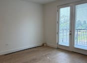 Thumbnail 9 of 24 - A room with a sliding glass door and wooden flooring.