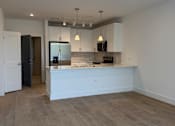 Thumbnail 8 of 24 - A kitchen with a white counter and wooden flooring.