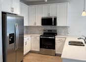 Thumbnail 6 of 24 - A kitchen with a stainless steel refrigerator, oven, and sink.
