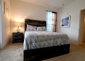 Thumbnail 27 of 44 - A bedroom with a bed, nightstand, and lamp.