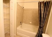 Thumbnail 28 of 44 - A white bathroom with a tub, shower, and open door to a pantry.