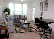 Thumbnail 1 of 44 - A living room with a grey couch, a coffee table, and a black piano.
