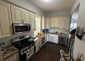 Thumbnail 4 of 8 - A kitchen with a black stove top oven and a microwave above it.
