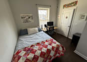 Thumbnail 6 of 8 - A bedroom with a bed, desk, chair, and window.