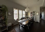 Thumbnail 1 of 8 - A dining room with a long table and chairs.
