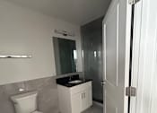 Thumbnail 19 of 20 - A white toilet in a bathroom with a white cabinet and a white door.