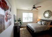 Thumbnail 33 of 44 - A bedroom with a bed, a ceiling fan, and a painting of a flower on the wall.