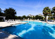 Thumbnail 19 of 44 - A large swimming pool with lounge chairs and palm trees in the background.