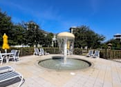 Thumbnail 21 of 44 - A fountain in the middle of a patio surrounded by chairs.