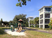 Thumbnail 18 of 44 - A playground with a slide and a building in the background.