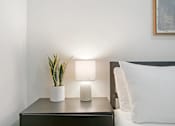 Thumbnail 18 of 27 - A bedside table with a plant and two lamps.
