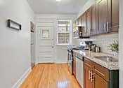 Thumbnail 19 of 27 - A kitchen with wooden floors and black appliances.