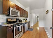 Thumbnail 20 of 27 - A kitchen with dark wood cabinets and a black stove top oven.