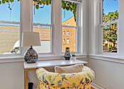 Thumbnail 4 of 27 - A yellow floral chair sits in front of a table with a lamp and vase on it.