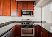 Thumbnail 69 of 86 - A kitchen with a black stove top oven and microwave above it.