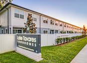 Thumbnail 1 of 18 - A sign for Lake Tavares Townhomes stands in front of a row of townhomes.