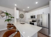 Thumbnail 8 of 18 - A modern kitchen with a white countertop and stainless steel appliances.