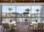 Thumbnail 24 of 46 - A patio with a table and chairs overlooking a pool and buildings.