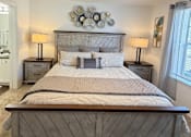 Thumbnail 46 of 48 - A bed with a wooden headboard and footboard with a white comforter and pillows.