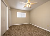 Thumbnail 16 of 24 - A room with a ceiling fan and carpeted floor.