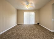Thumbnail 18 of 24 - A room with a ceiling fan and carpeted floor.